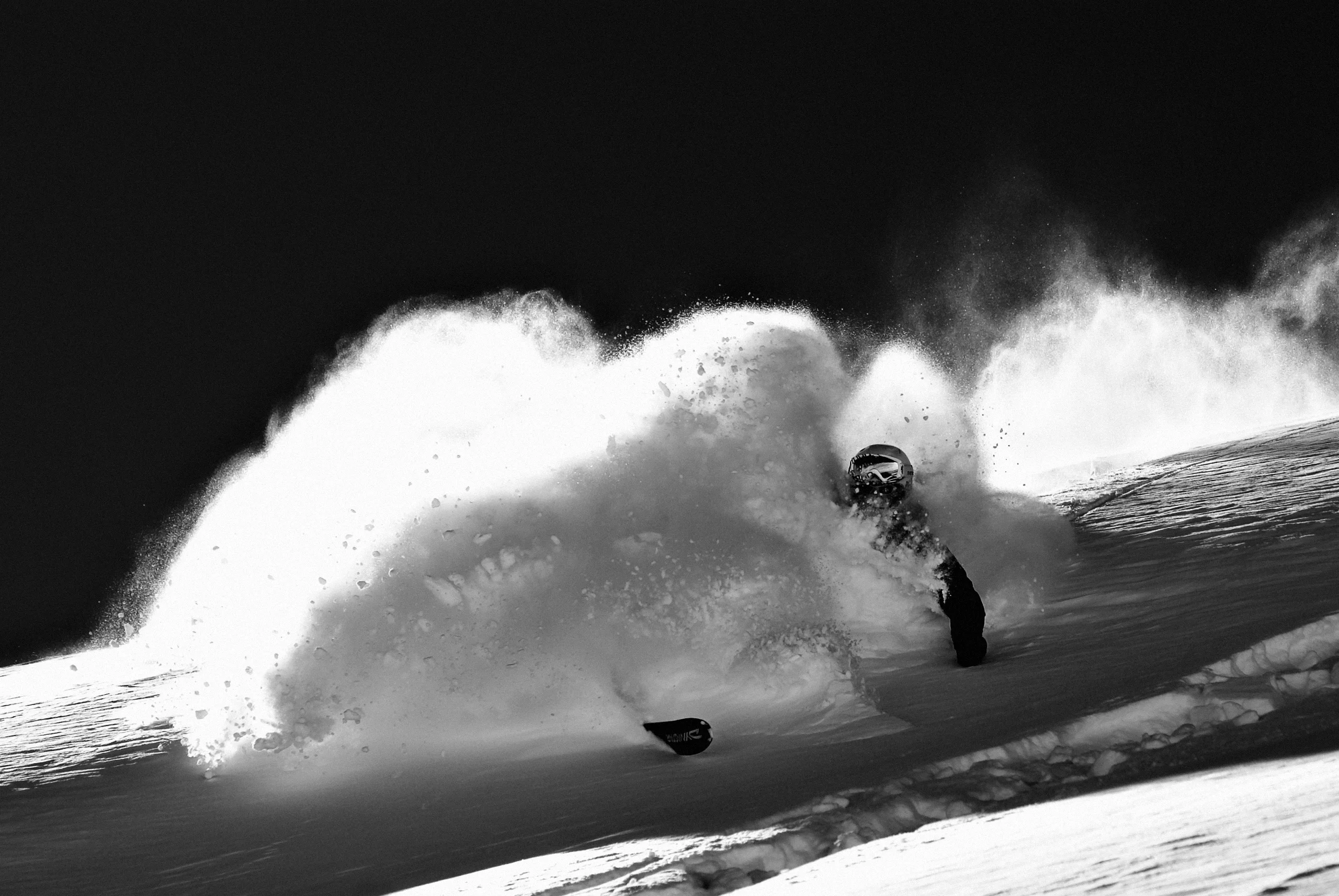 Face-shot en poudreuse, panache de neige explosif sur pente sombre