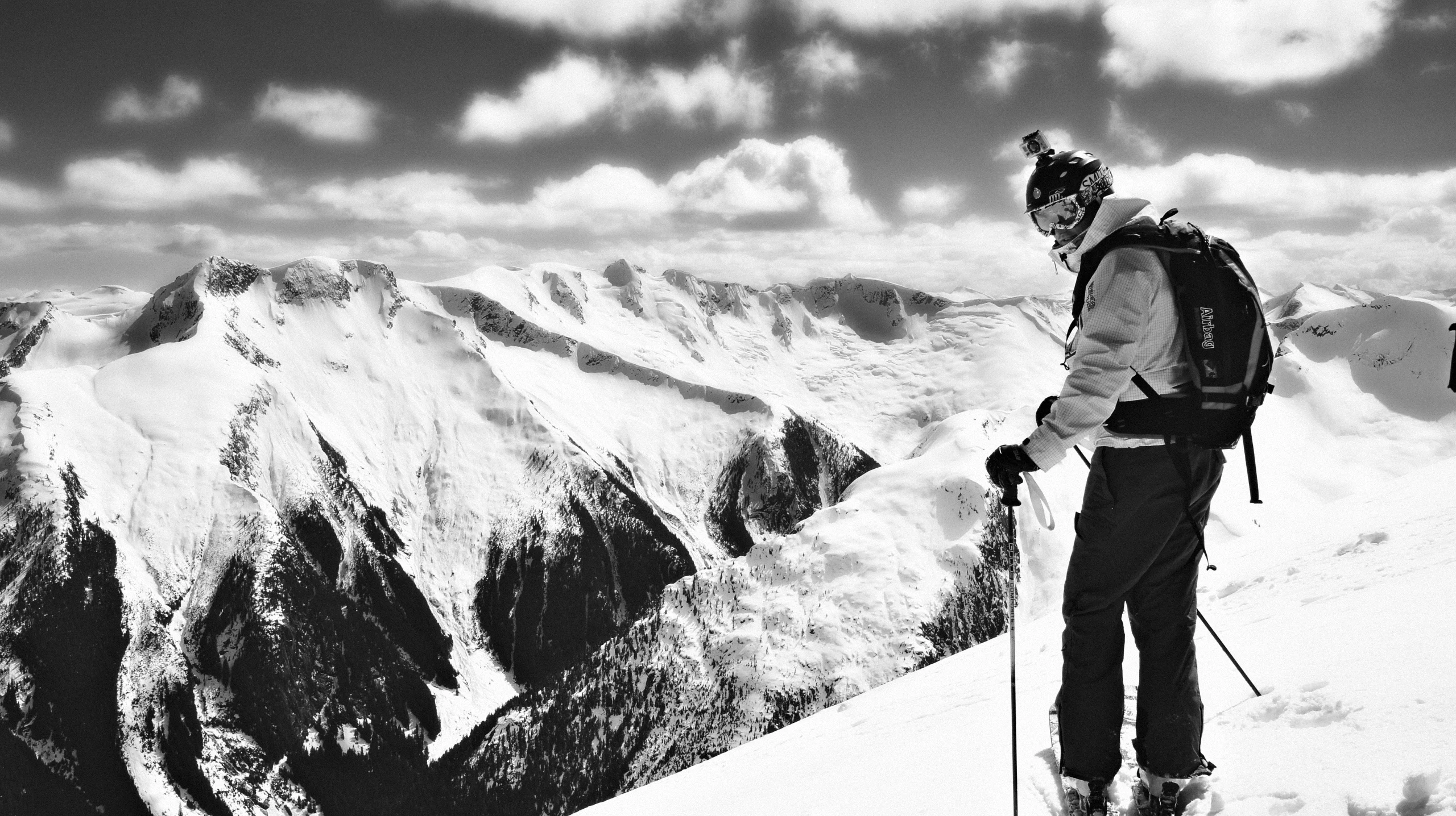 Skieur sur une crête face à la vallée et aux sommets