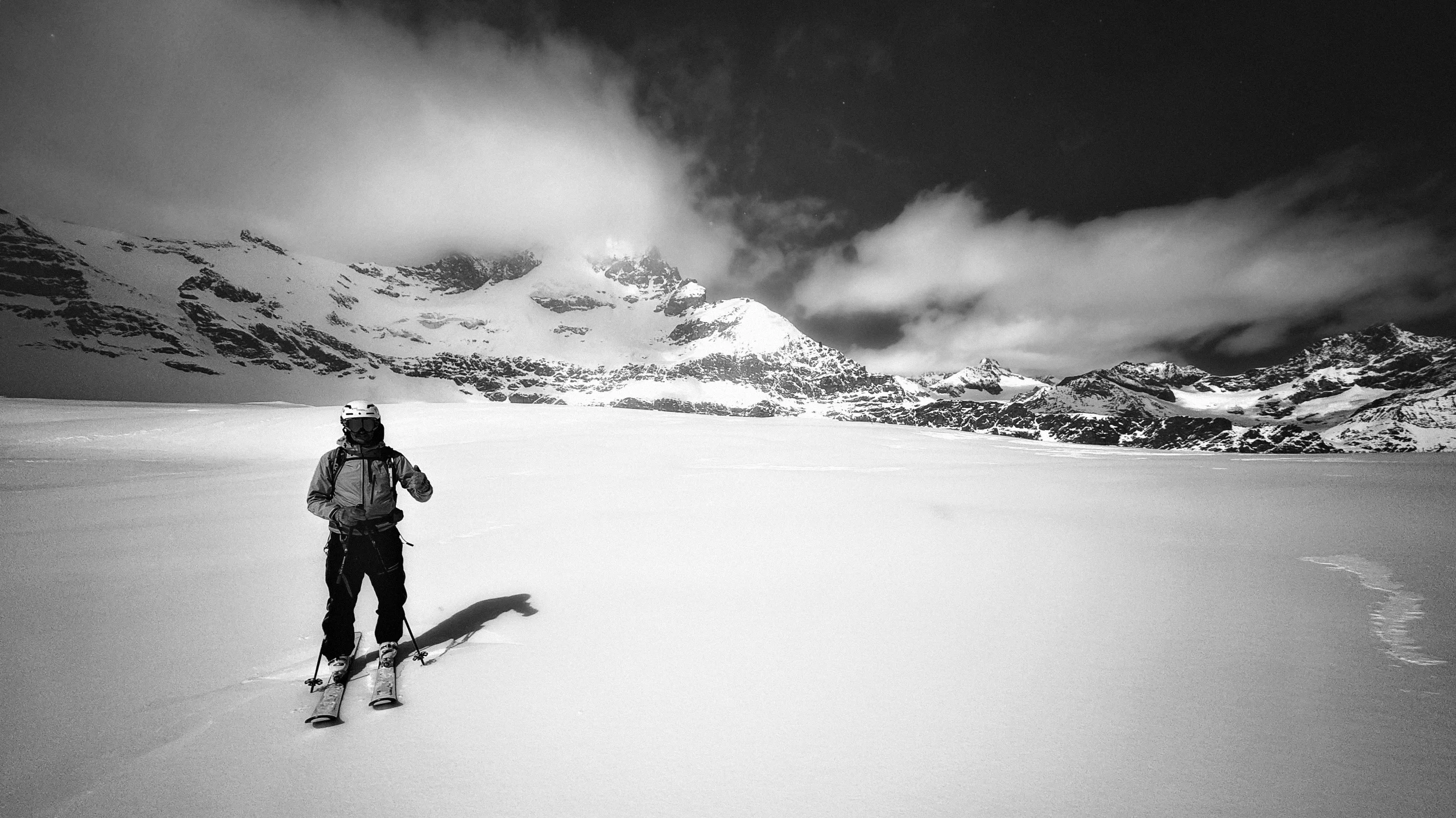 Skieur solitaire traversant un lac gelé sous un ciel chargé